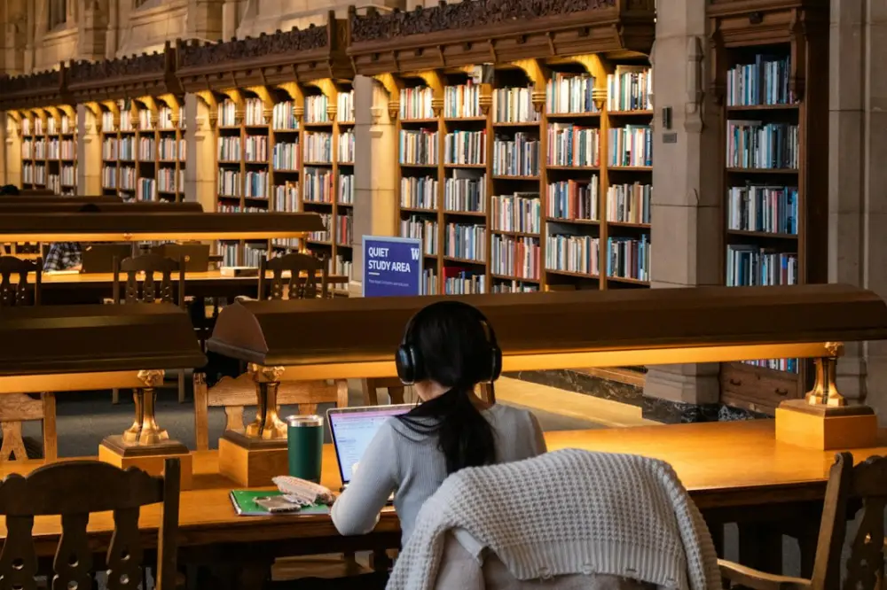 Student studies at a library with books, illustrating academic e-journals
